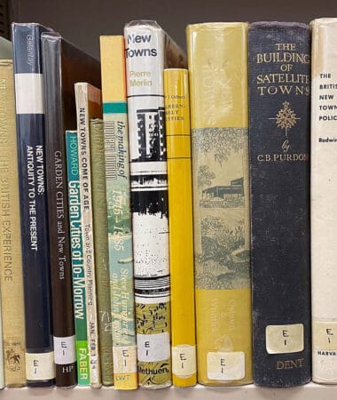 A photograph of a set of books on a library shelf about the creation of New Town in Harlow. The books vary in size and colour.