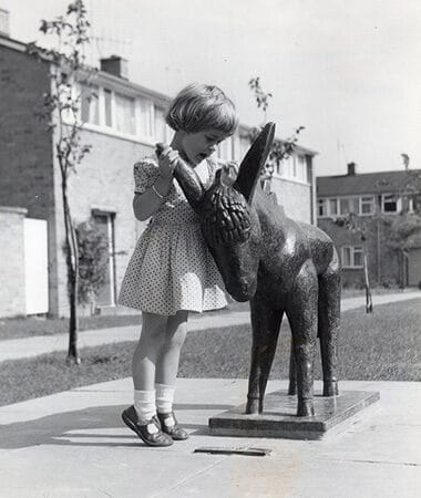 Grey Scale Photograph of a Young Girl with a Statue of a Donkey
